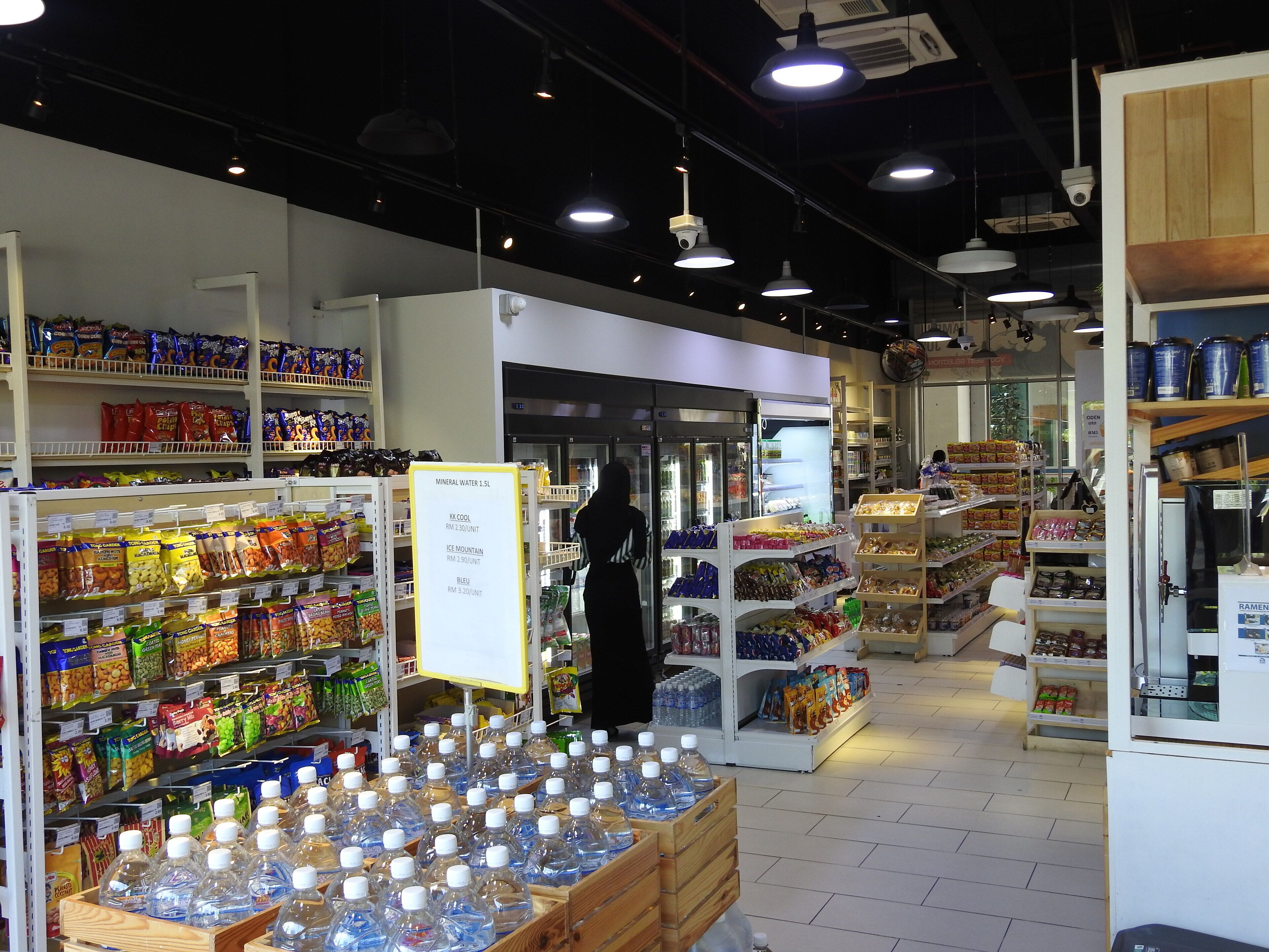 A grocery store interior with shelves stocked with snacks, bottled water, and other beverages.