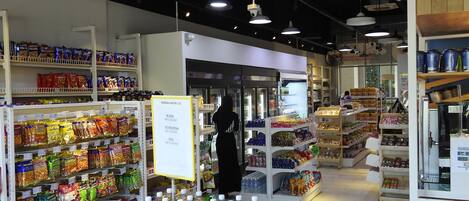 A grocery store interior with shelves stocked with snacks, bottled water, and other beverages.