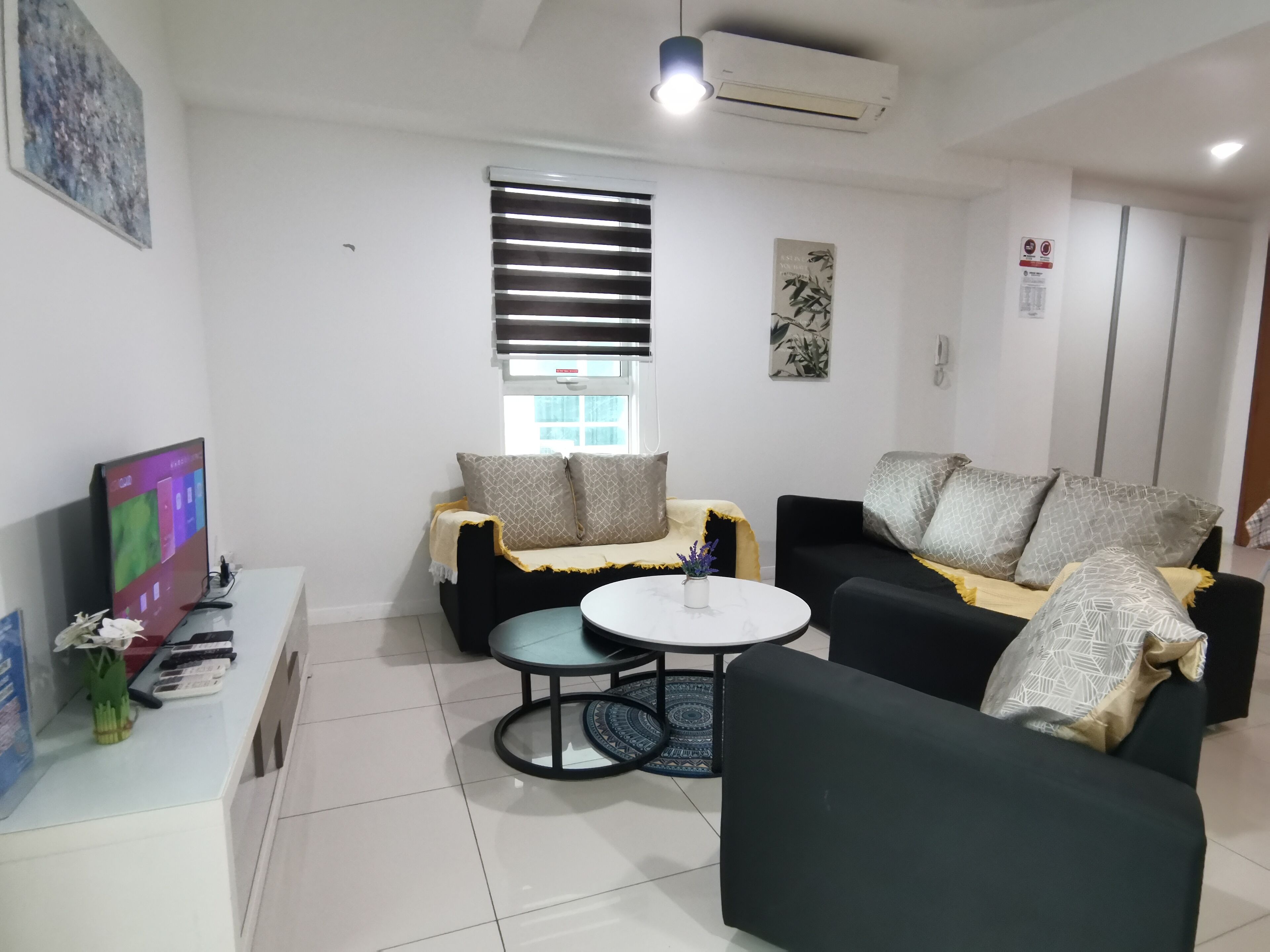 A modern living room with a sofa, a smaller couch, a coffee table, and a TV on a stand.