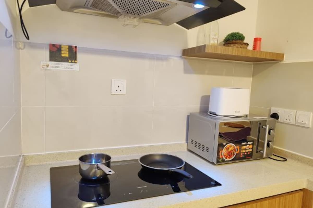 Una cocina con placa de inducción, microondas y tostadora.