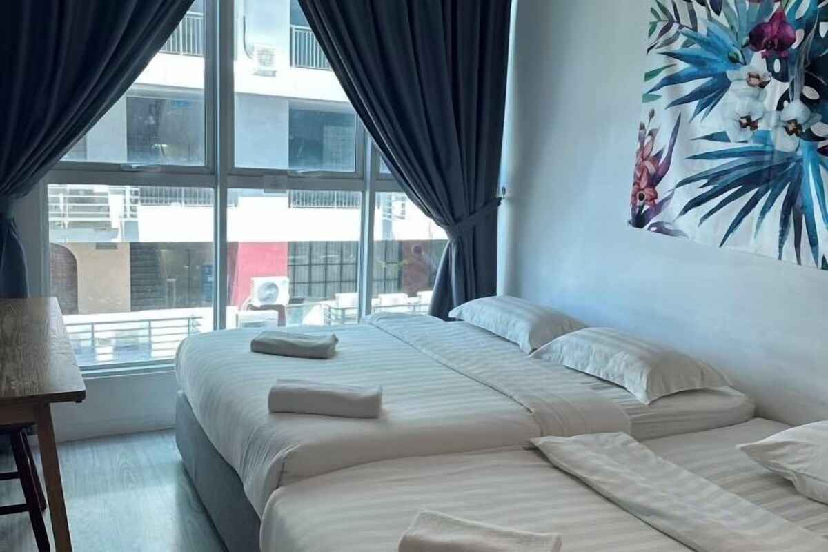 Une chambre d’hôtel avec un grand lit, un bureau et une vue sur la ville par la fenêtre.