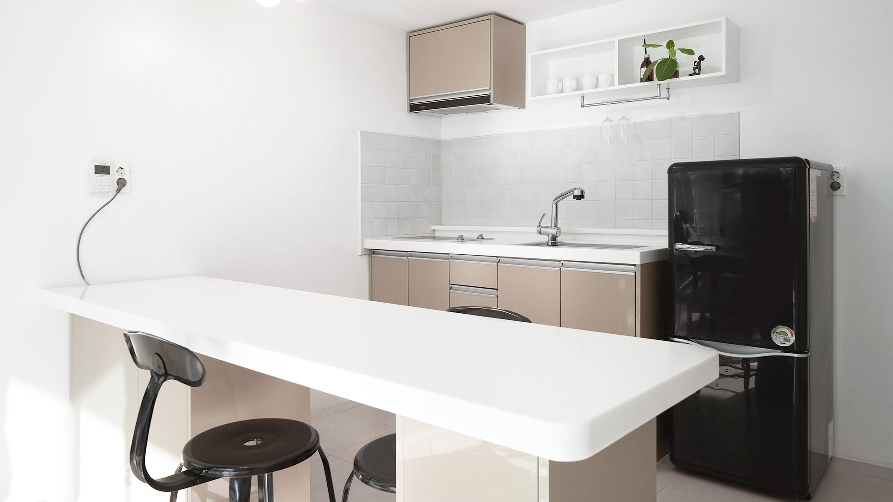 Une cuisine moderne avec un plan de travail blanc, un réfrigérateur noir et un four encastré.