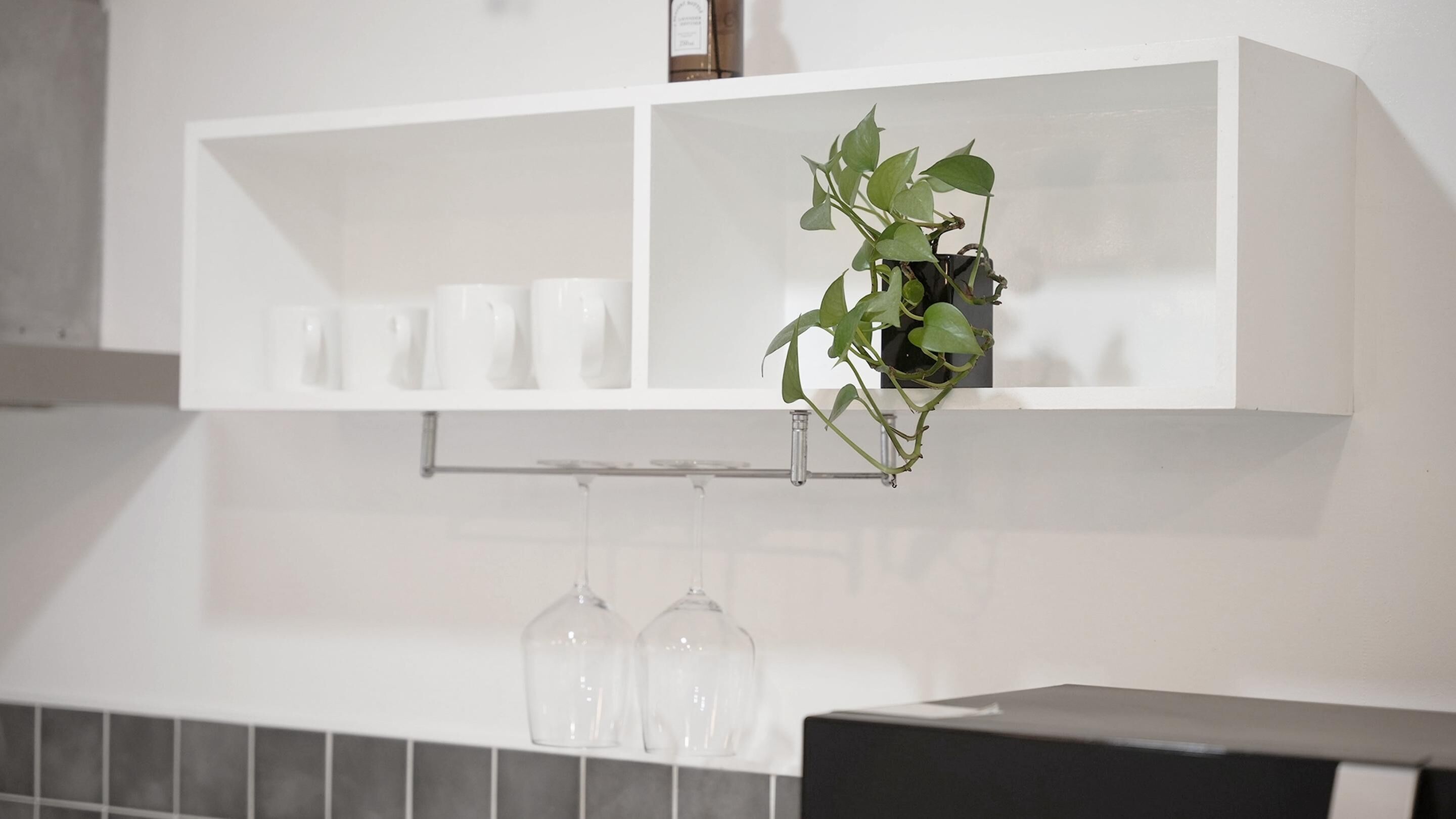 A white shelf with a potted plant and several clear glass bottles.