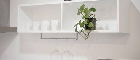 A white shelf with a potted plant and several clear glass bottles.