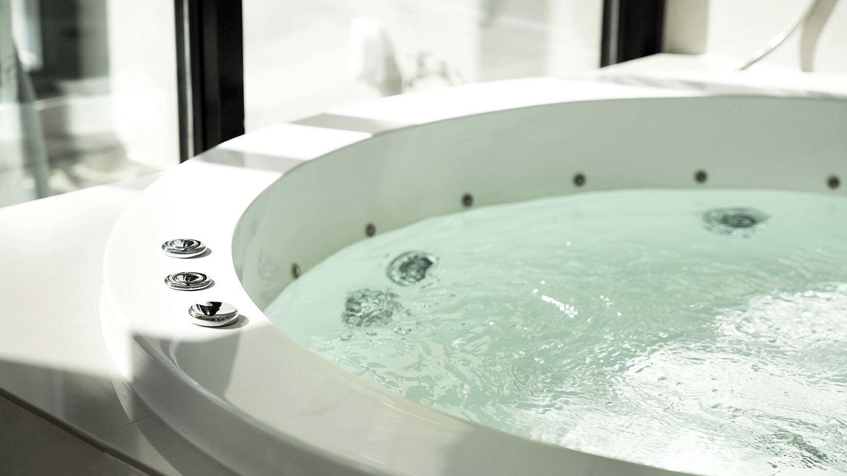A hot tub with jets, a control panel, and a window.