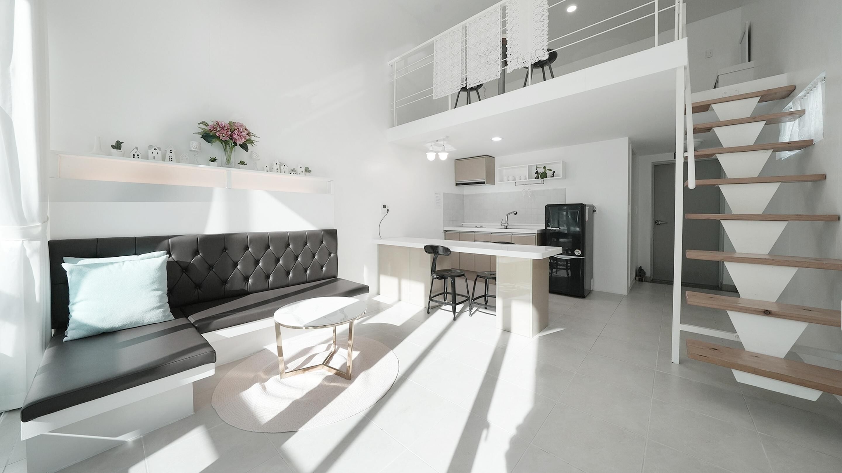 A modern apartment with a living area, kitchen, and a loft bedroom.