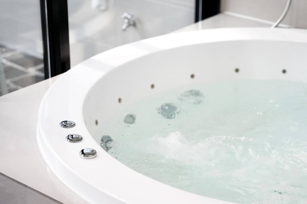 Une salle de bain moderne avec une baignoire blanche, une douche en verre et un robinet apparent.