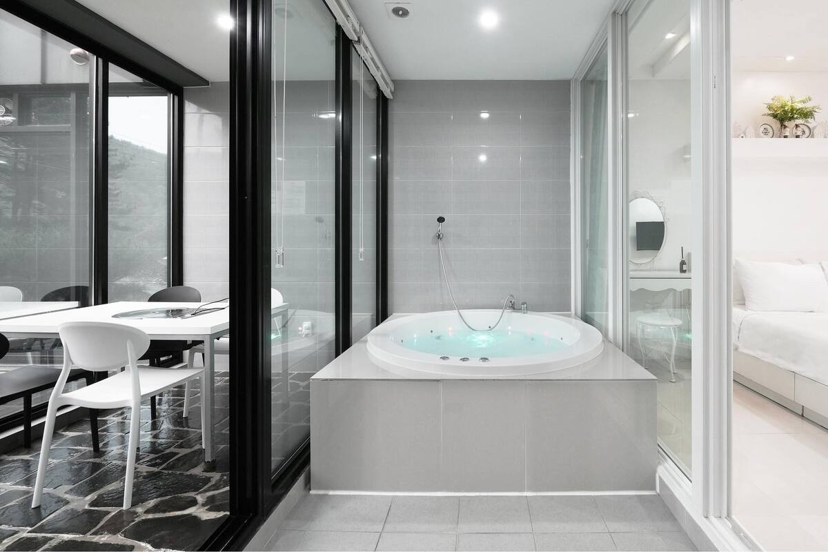Une salle de bain moderne avec une grande baignoire, une douche à l’italienne et un meuble-lavabo blanc.