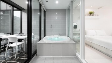 Un baño moderno con una bañera grande, una ducha con cerramiento de vidrio y un tocador blanco.