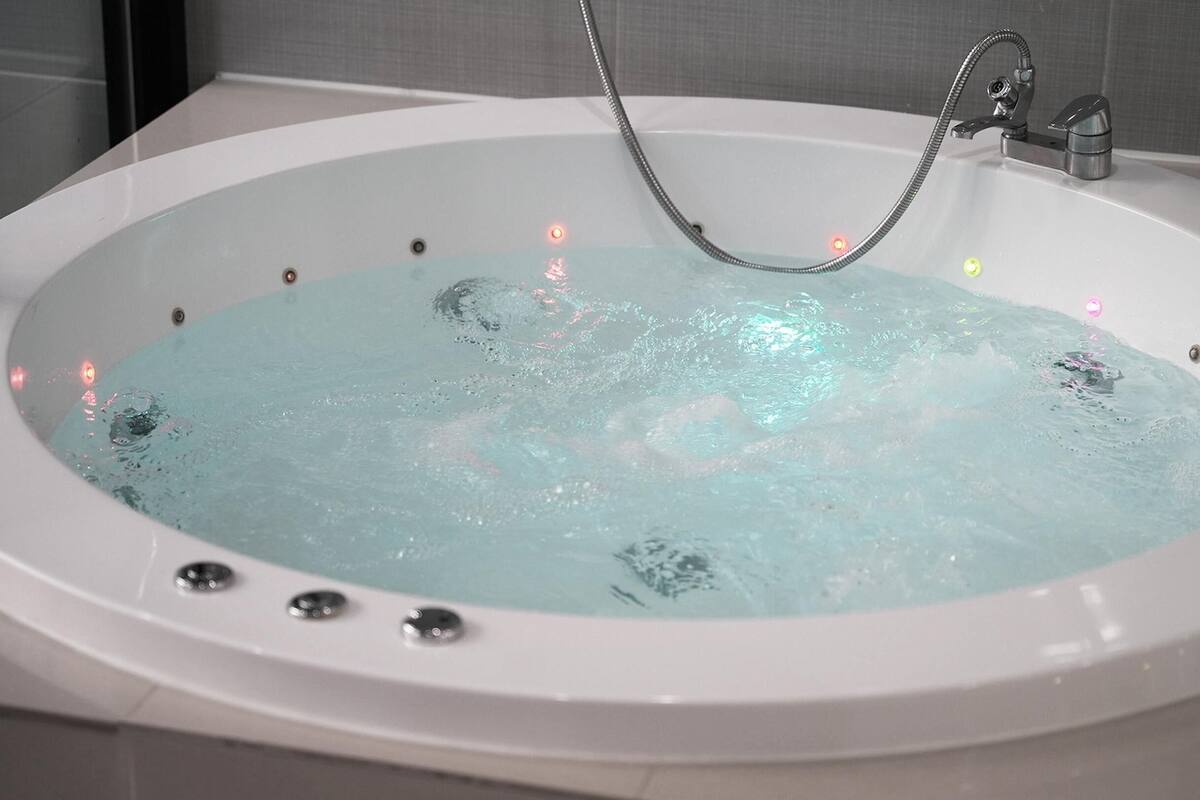 Une baignoire blanche dotée d’une pomme de douche et de plusieurs jets.