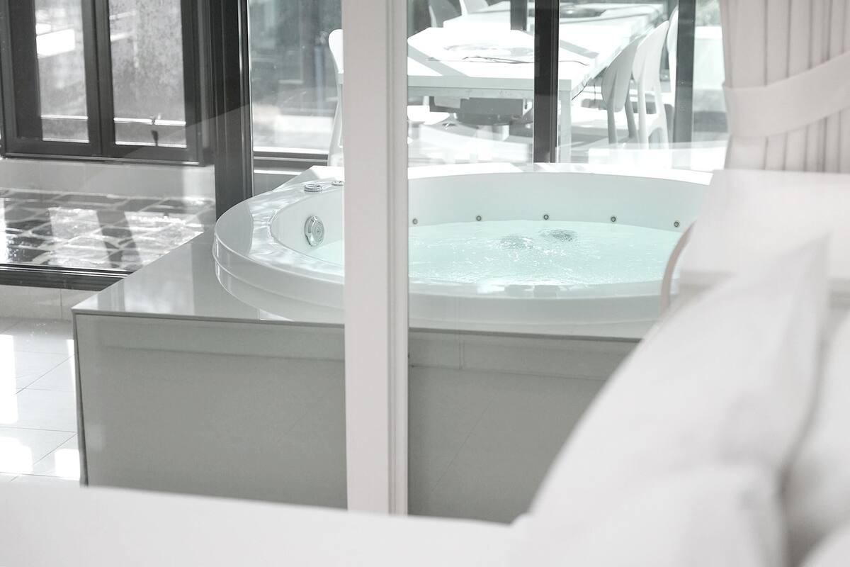 Une salle de bain moderne dotée d’une grande baignoire, d’une douche à parois de verre et offrant une vue sur l’extérieur.