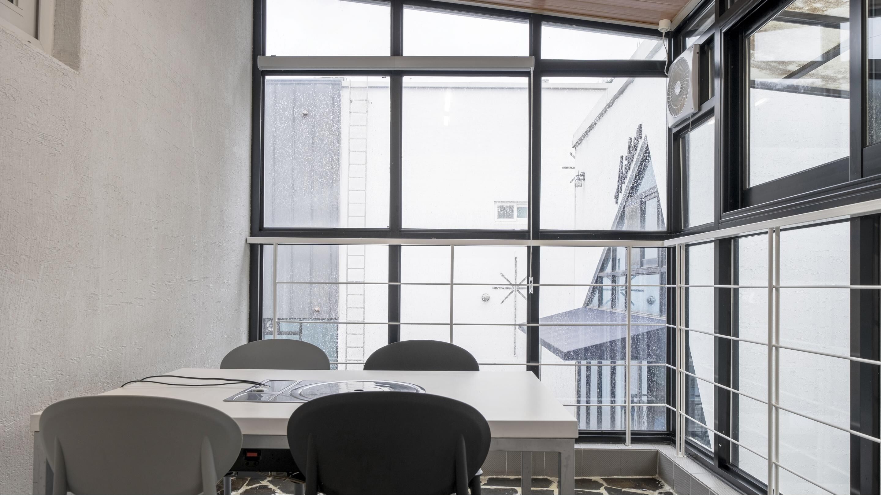 A conference room with a large window, a table, and four chairs.