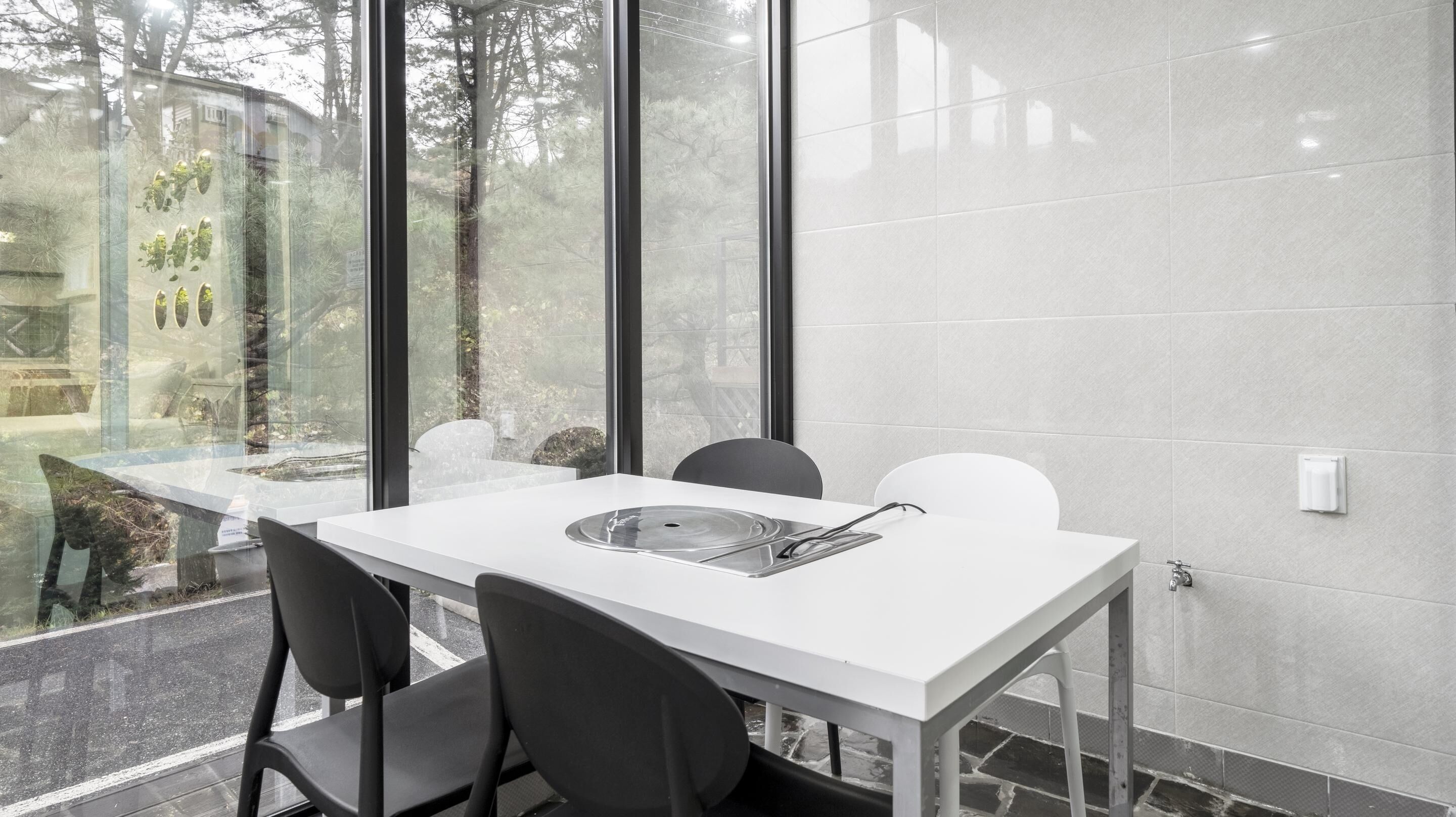 A modern conference room with a white table, black chairs, and a glass partition.