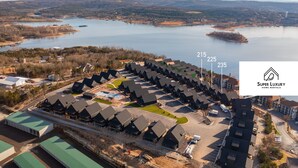 Luchtbeeld van een woongebied met meerdere huizen, een groot waterlichaam en het logo van 'Super Luxury Home Rentals'.