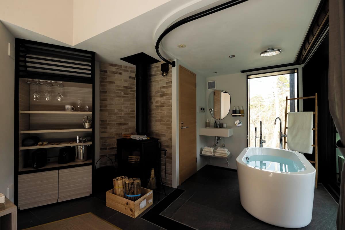 A modern bathroom with a freestanding bathtub, a built-in shower, and a wooden shelf unit.