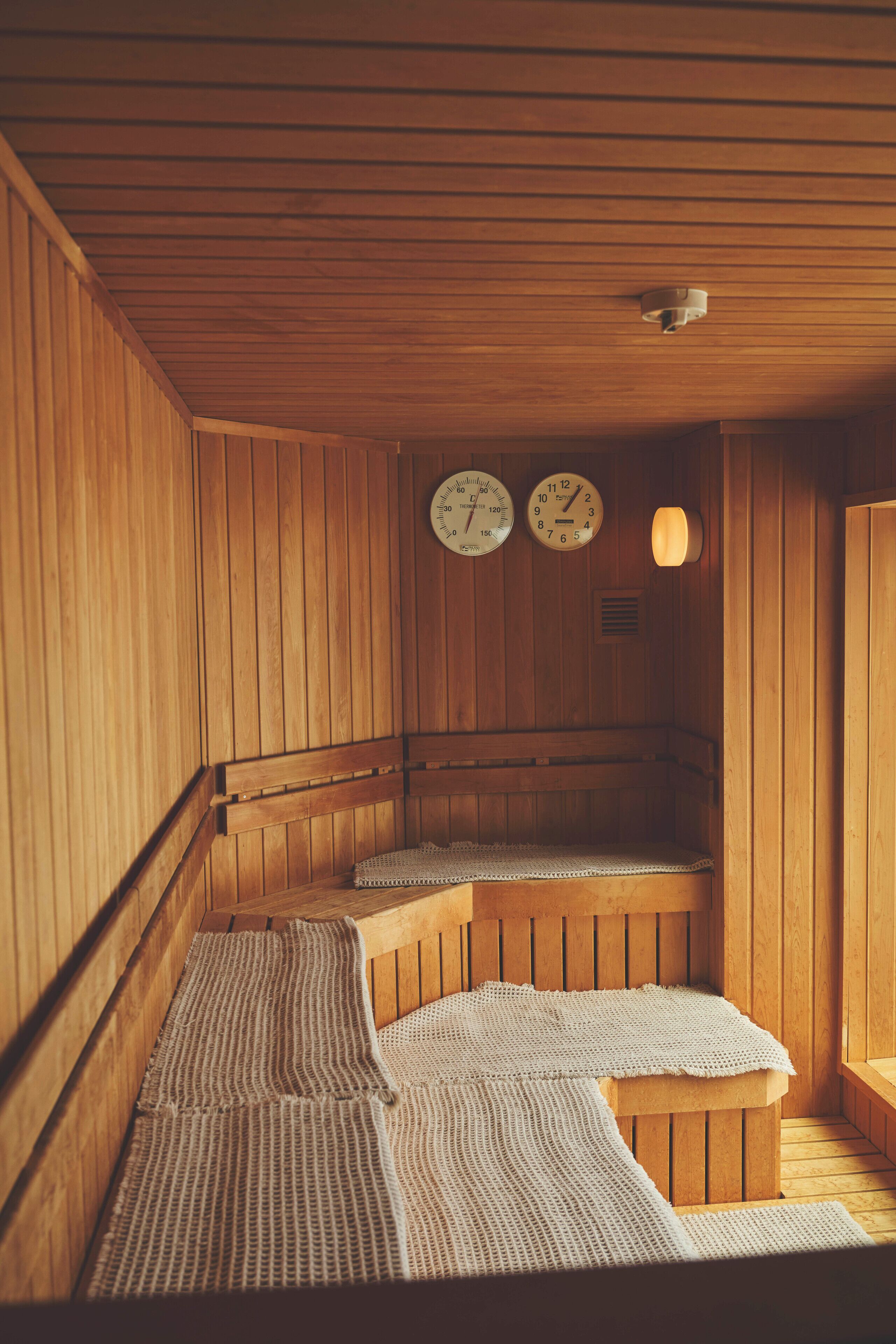 Una sauna de madera con bancos y un reloj colgado en la pared.