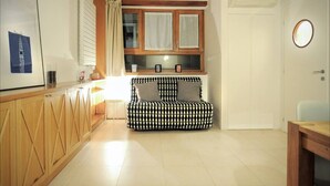 Una sala de estar acogedora con un sofá estampado, armarios de madera y una ventana con cortinas.