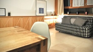 Una habitación con una mesa de comedor de madera, un sofá estampado y un cuadro en la pared.