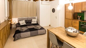 Un dormitorio pequeño con cama, mesita de noche y una kitchenette.