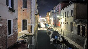 Un canal estrecho en un pueblo histórico europeo, bordeado por edificios tradicionales y barcos.