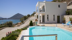 Een moderne villa met een zwembad, een balkon en uitzicht op zee en bergen.