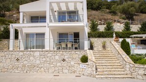 Un bâtiment moderne à deux étages, doté d’une façade en pierre, d’un balcon avec des sièges et d’une enseigne indiquant le nom « Villa Stella ».