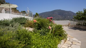 Un jardin aménagé avec un sentier en pierre, un fauteuil suspendu et une vue sur une montagne.