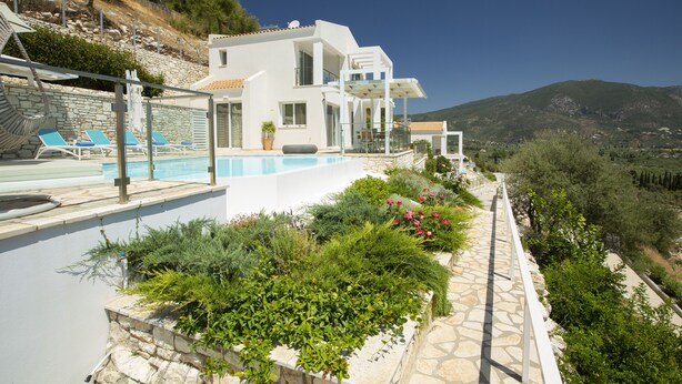 Une villa moderne dotée d’une piscine, d’un jardin luxuriant et offrant une vue sur les montagnes.