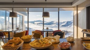 A dining area with a mountain view, featuring a table set with bread, salad, and meat. - Gogi Resort (Kazbegi)