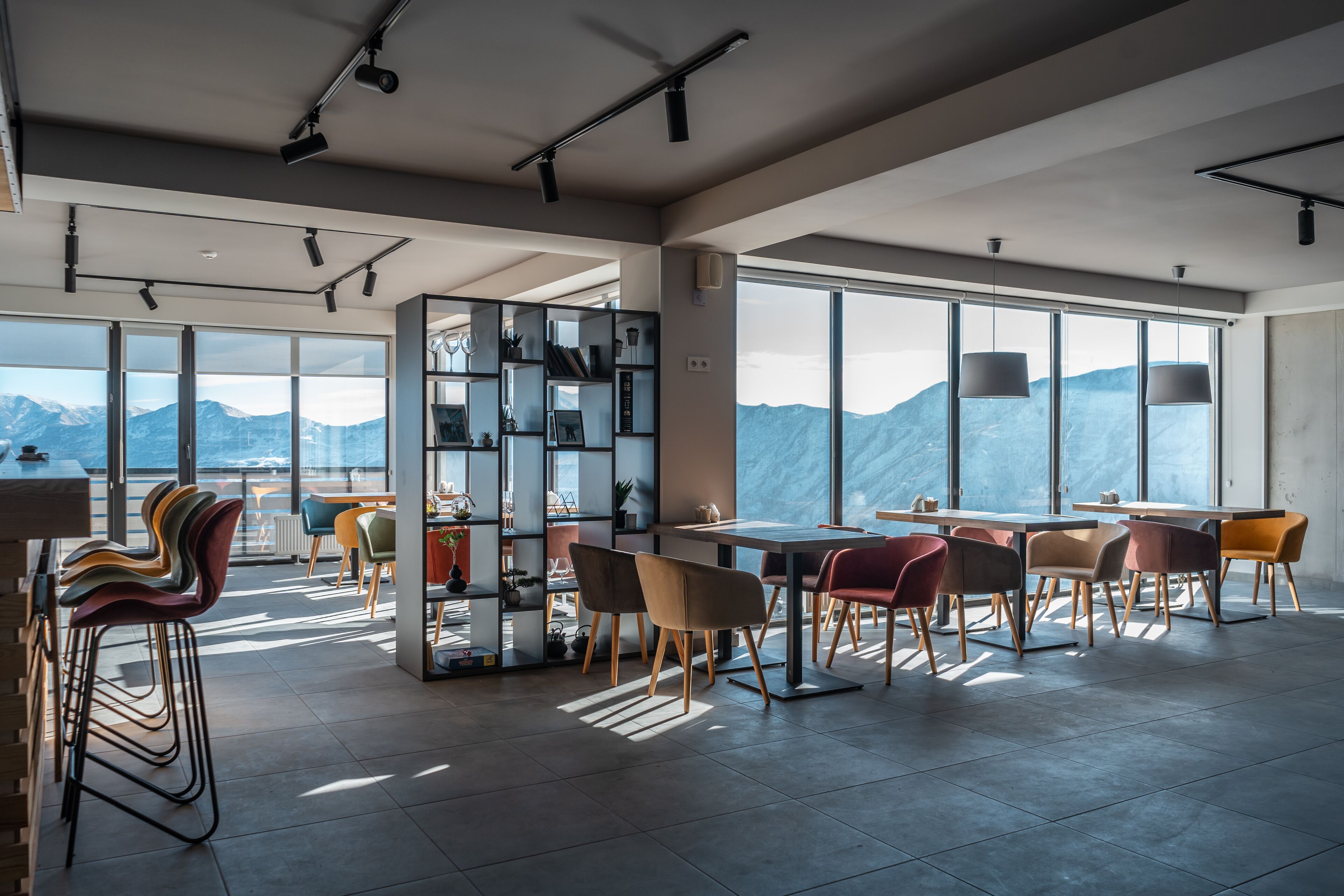 A modern dining area with large windows, a central table, and colorful chairs.