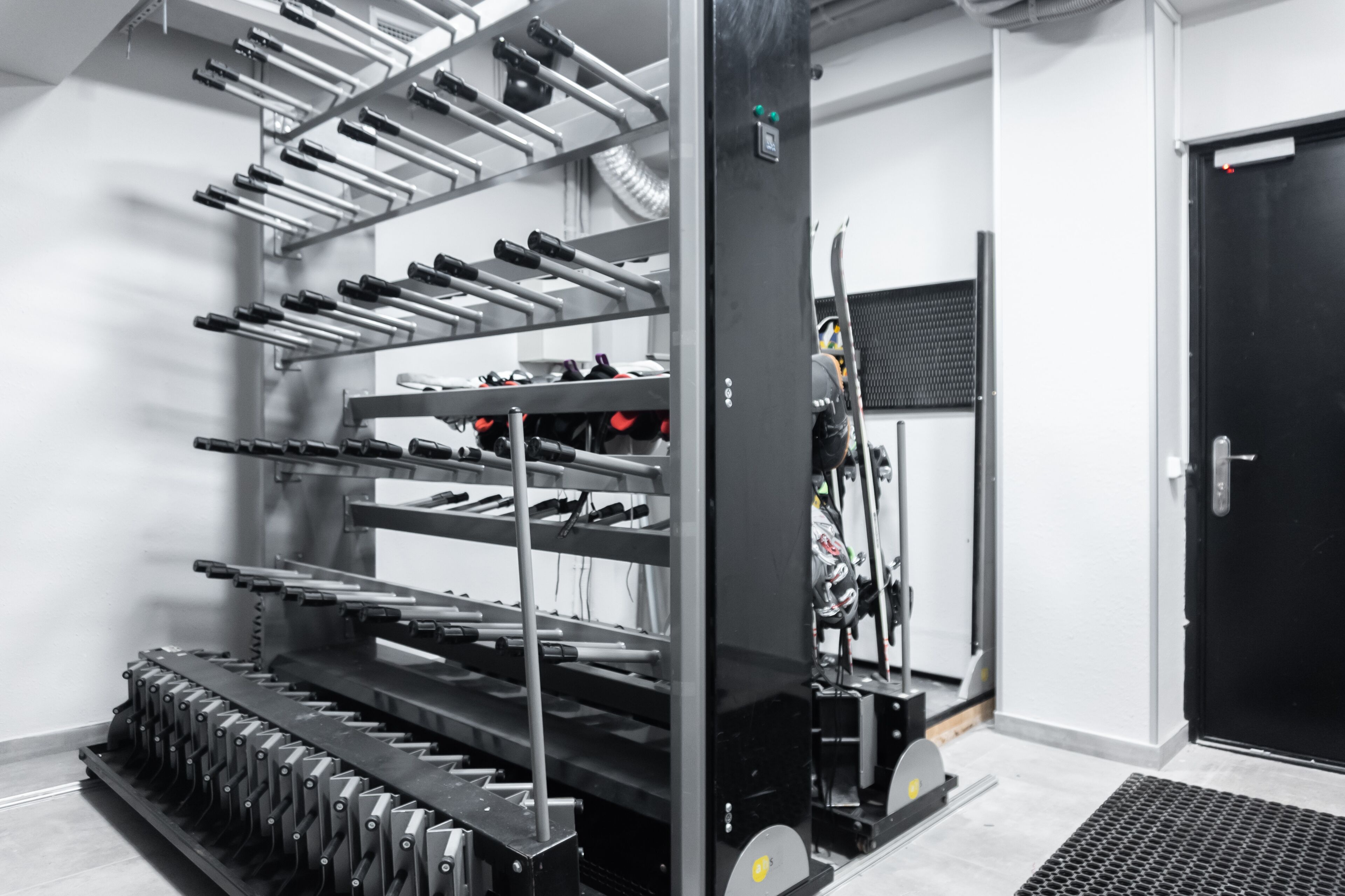 A gym with multiple rows of dumbbells, a treadmill, and a door with a security keypad.