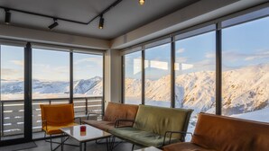 A modern interior with large windows, a sofa, a table, and a chair. - Gogi Resort (Kazbegi)