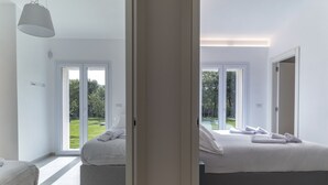 Ein modernes Hotelzimmer mit zwei Betten, großen Fenstern und Blick auf eine grüne Landschaft.