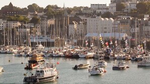 A marina with numerous boats docked, surrounded by buildings and trees. - The Pandora Hotel (St. Peter Port)