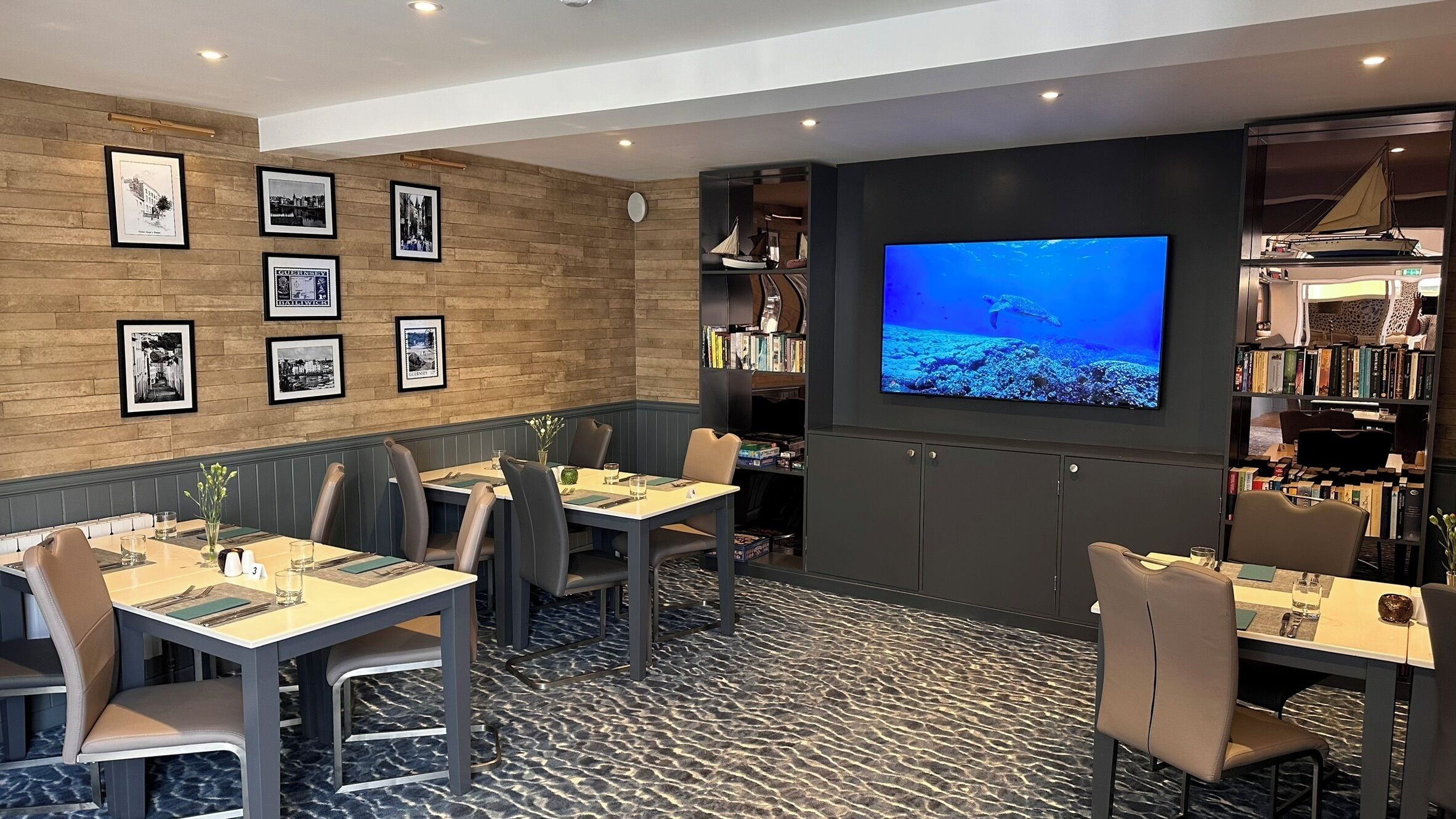 A restaurant with tables, chairs, a wall-mounted TV, and framed pictures.