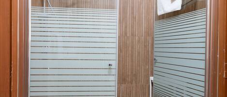 Una ducha a nivel con puerta de cristal, paneles de madera y suelo de baldosas.