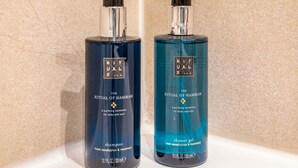 Deux bouteilles de shampoing et de gel douche de la gamme Ritual of Hammam, posées sur une surface blanche.