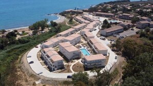 An aerial view of a coastal resort with multiple buildings, a swimming pool, and a beach. - Une Vague de Plaisir en Famille (Linguizzetta)