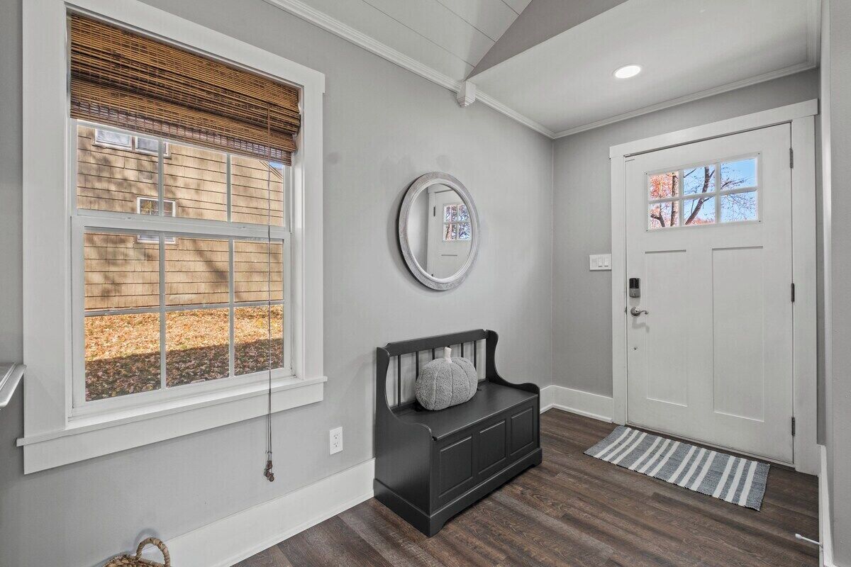 A hallway with a bench, a door, and a window with blinds.