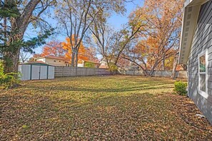 A residential backyard with a wooden fence, a shed, and trees with autumn foliage. - Mission Outlook - Gorgeous Home + Pet Friendly (Mission)
