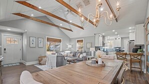 Un salón amplio con una gran mesa de comedor de madera, un conjunto de sofás y una cocina al fondo.