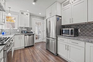 Una cocina moderna con electrodomésticos de acero inoxidable, armarios blancos y un salpicadero con diseño.
