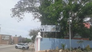 Placa da Heba Guest Lodge, com parede azul e cerca branca.