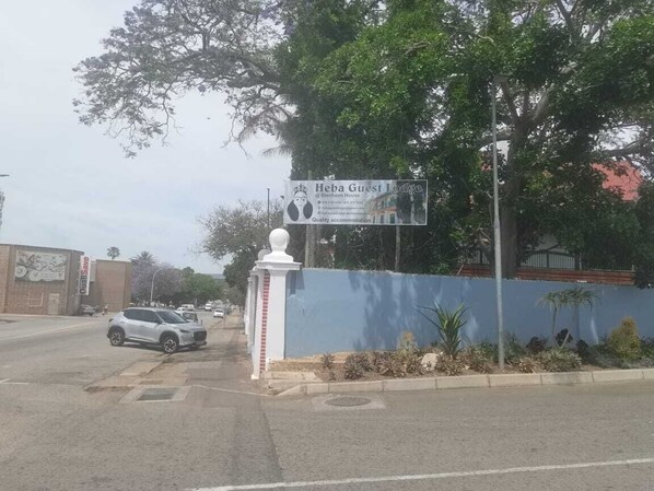 A sign for Heba Guest Lodge with a blue wall and a white fence.