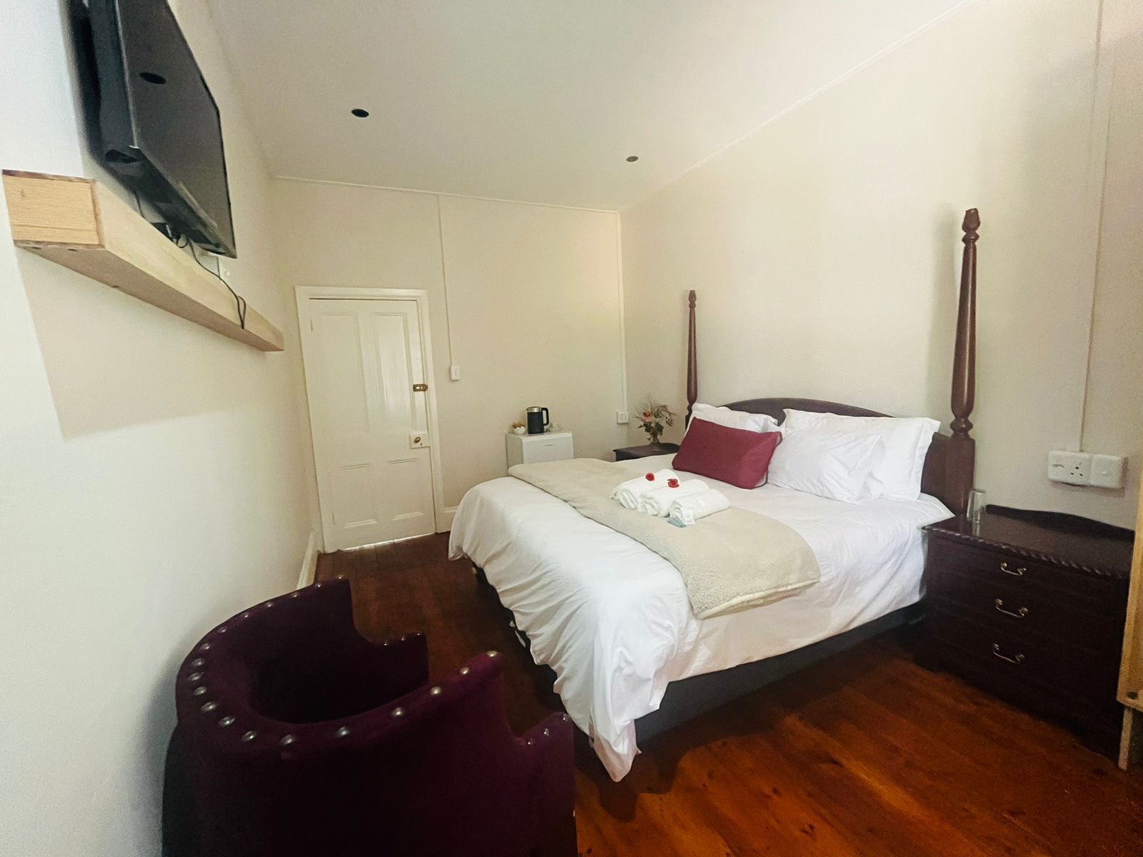A neatly arranged hotel room with a bed, bedside table, and a television mounted on the wall.