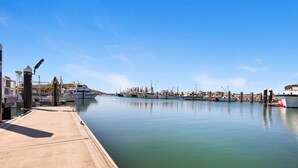 A marina with various boats docked, a concrete dock, and a clear blue sky.