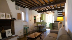 Un salon chaleureux avec un plafond en bois, un tabouret vert, une table basse en bois et un canapé.