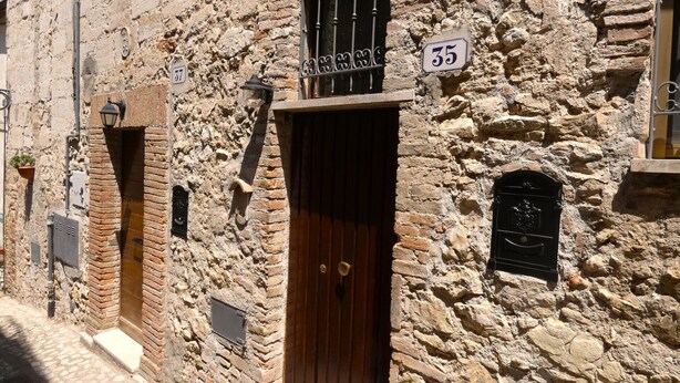 A stone building with a wooden door and a window with metal bars. There is a sign above the door with the number 35. - Scappo in Umbria, CasaLina (Amelia)