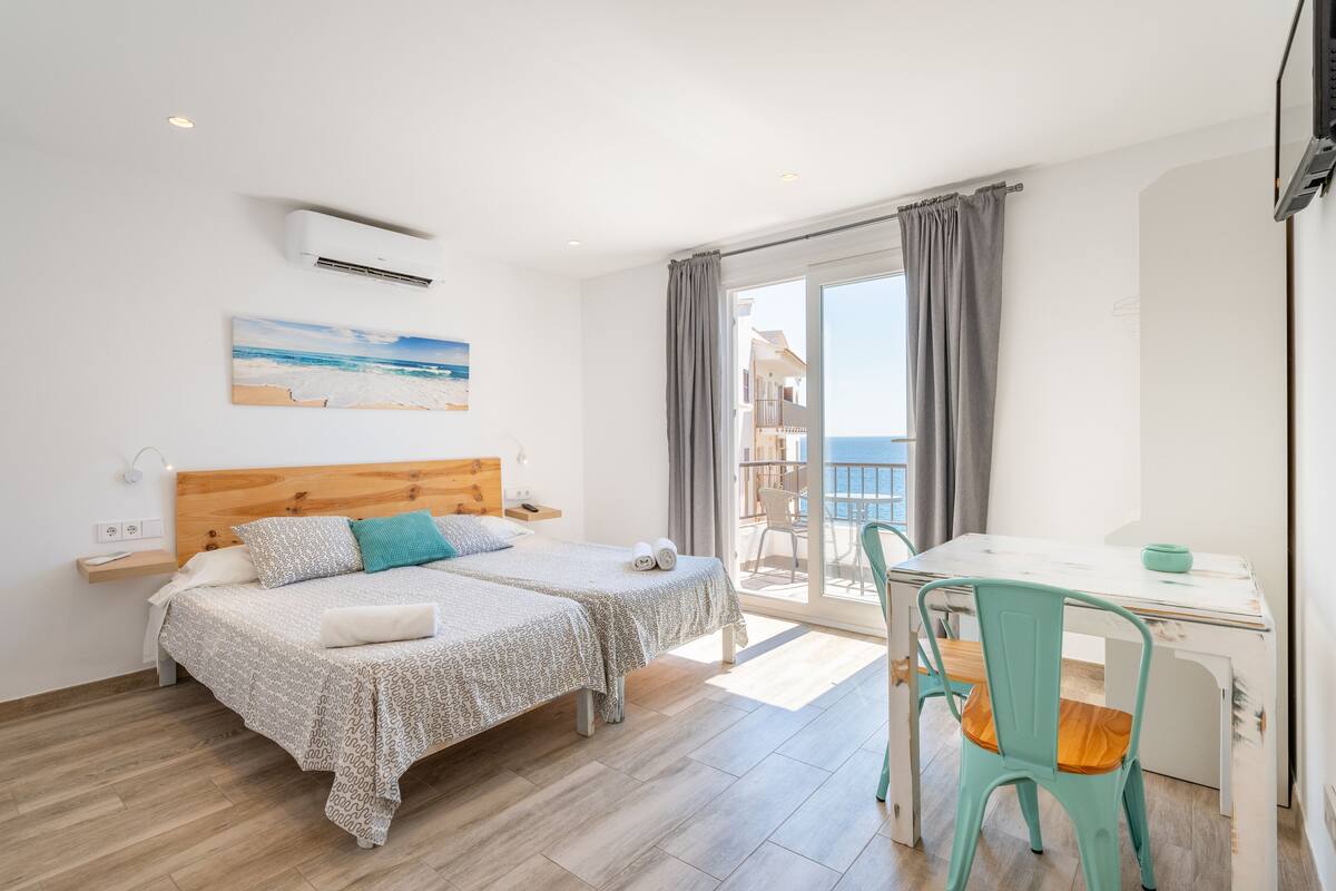 Un dormitorio con dos camas, un balcón y una zona de comedor.