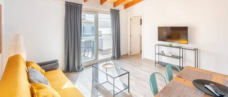 Una sala de estar moderna con un sofá, una mesa de centro de vidrio y un televisor sobre un mueble.